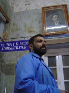 Father Tomy in front of a picture of Dr Billimoria, the founder of the Bel-Air Hospital